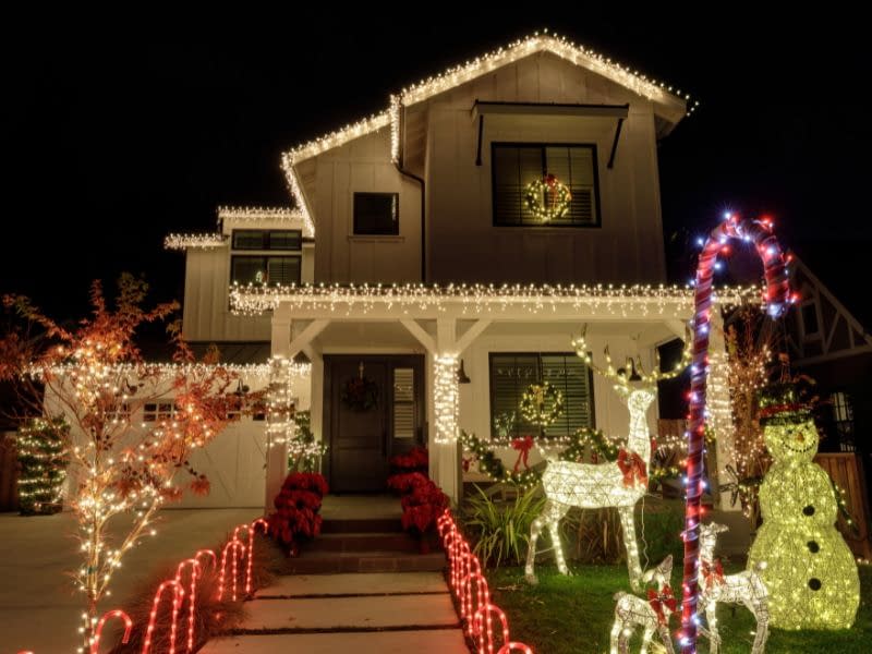 Beautiful house in Phoenix decorated with bright white Christmas lights, featuring illuminated reindeer and a snowman in the front yard.
